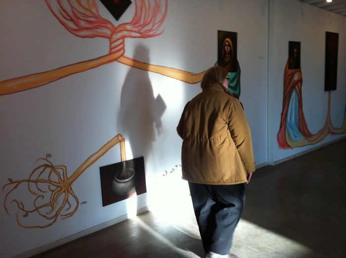 A community member adds the concept of light and shadow during the current art exhibit at La Casita in Syracuse, N.Y.